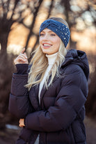 Model wearing the Britt's Knits Starlight blue twist-front knit headwarmer with pearl and rhinestone details styled with a winter jacket for a chic cold-weather look.